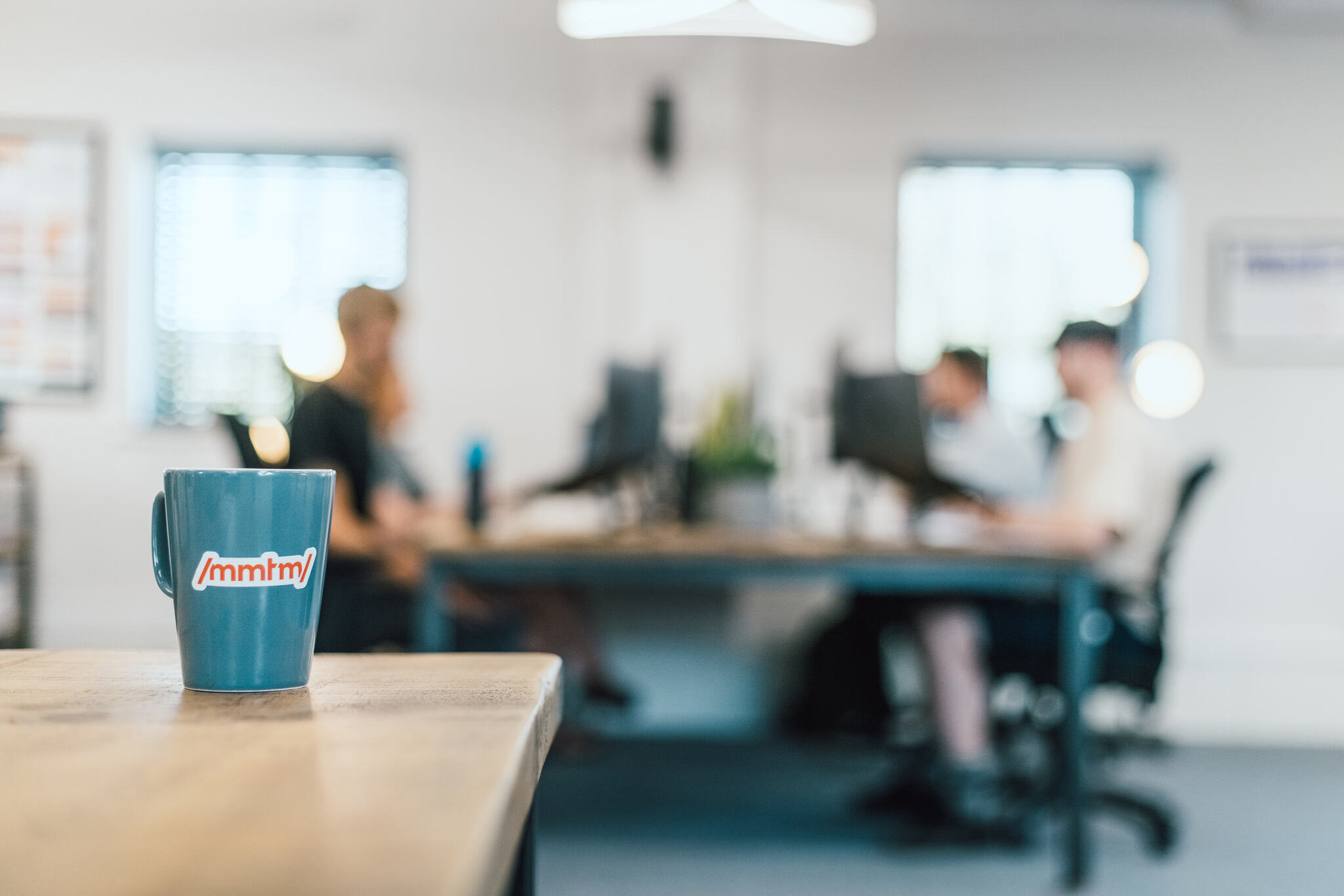 some mmtm developers at a desk in the background behind a mmtm-branded mug